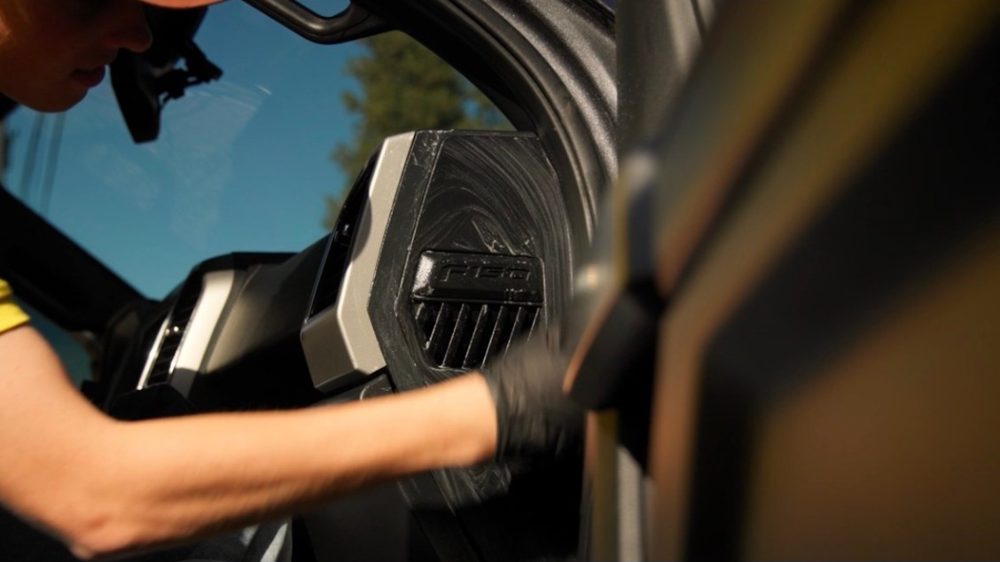 A gloved hand wiping a truck dashboard vent