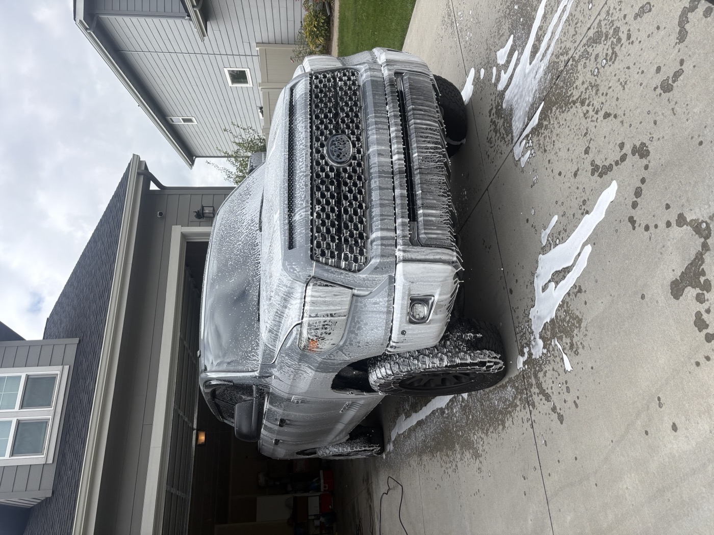 A Toyota Tundra covered in thick wash foam in a driveway